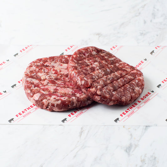 Two minced lamb patties on feather & bone branded paper.