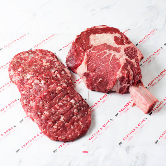 4 160g Grass-Fed Beef Patties and a 1kg Grain-Fed Bone-In Ribeye on Feather & Bone branded paper.