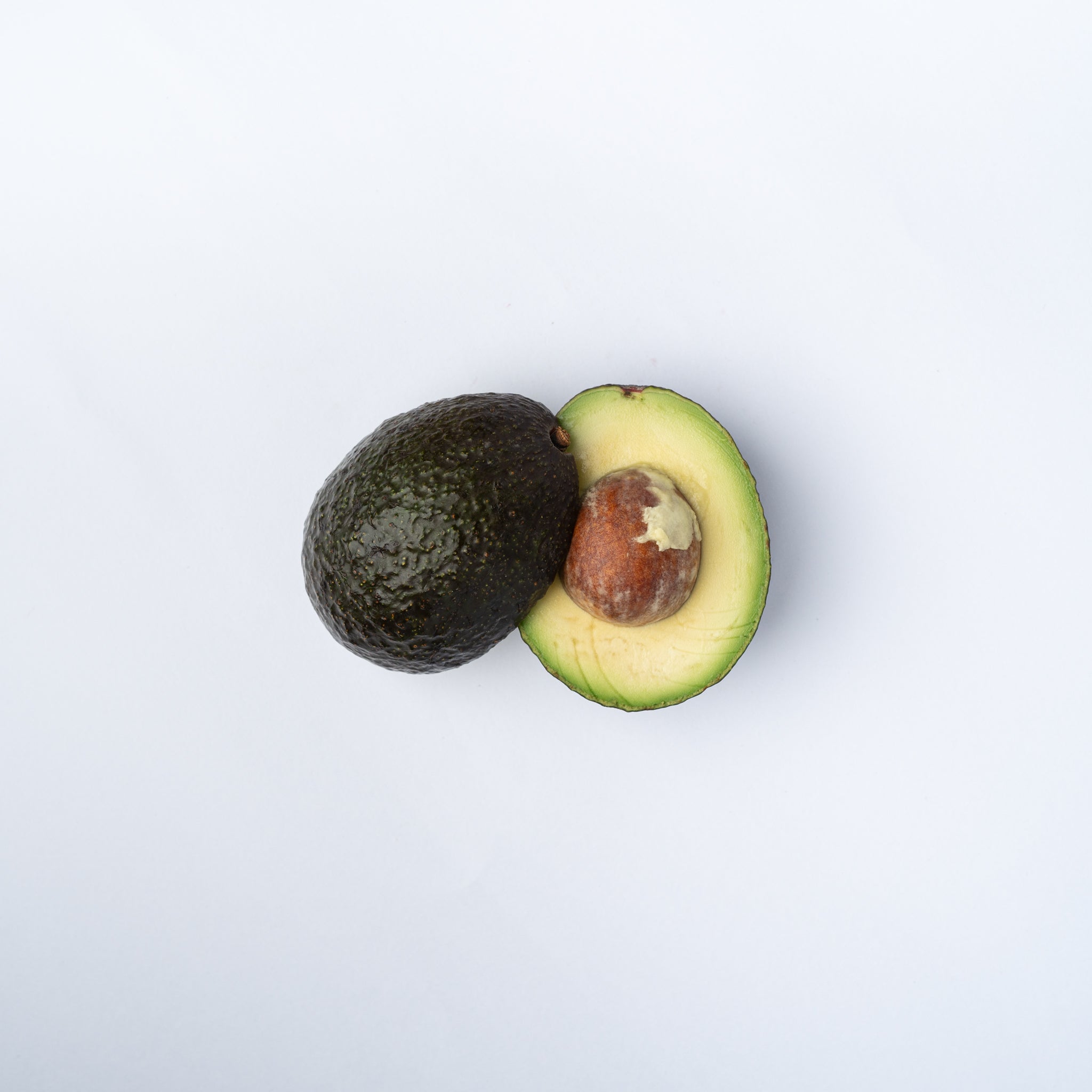 A ripe avocado cut in half with the stone and green flesh showing.