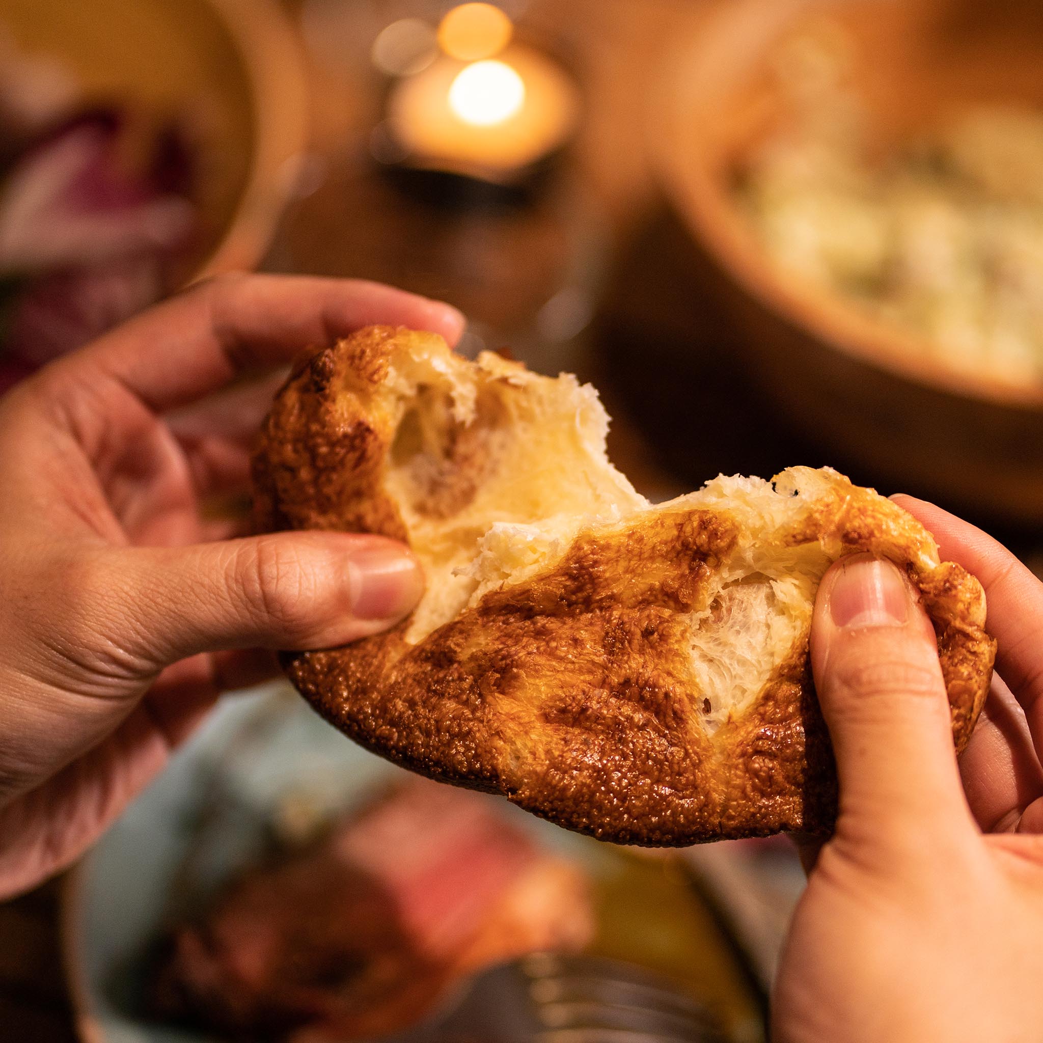 A yorkshire pudding being pulled apart by two hands.