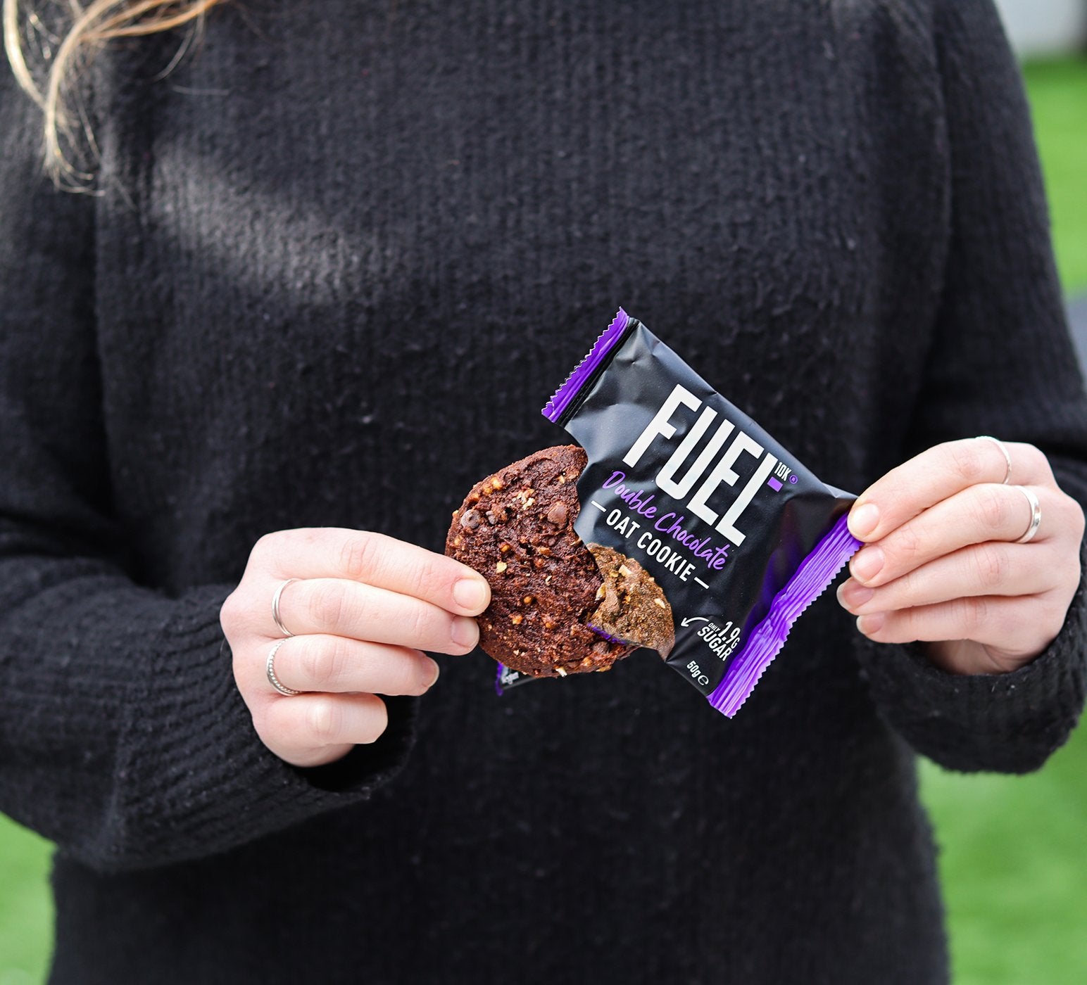 Someone holding a A FUEL10K Double Chocolate Cookie in a black package.