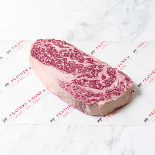 A Wagyu Ribeye MBS7 beef steak on a marble slab.