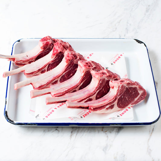 A rack of lamb cutlets on a navy and white enamel plate.