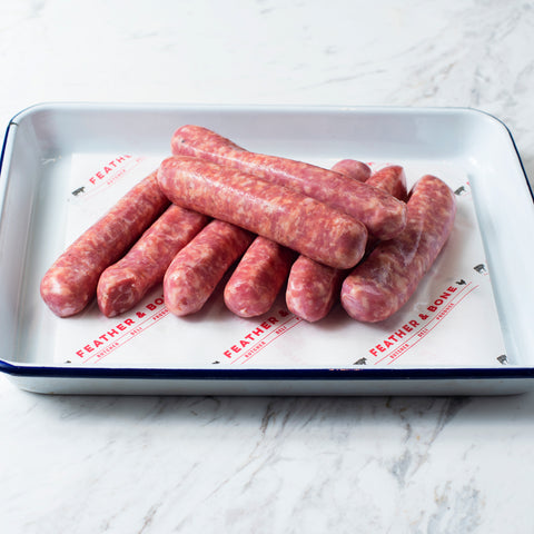 A white and navy enamel tray of chipolata sausages.