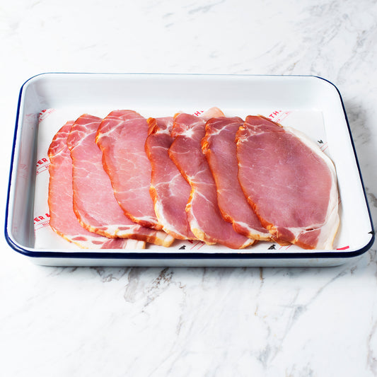 A tray of canadian back bacon on Feather & Bone branded paper.