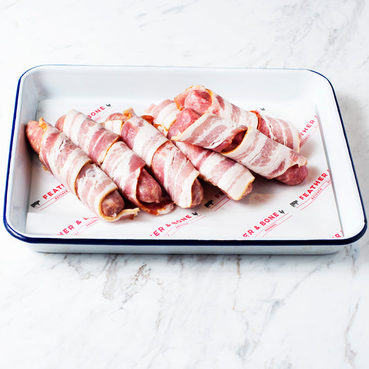 An enamel tray of sausages wrapped in bacon.