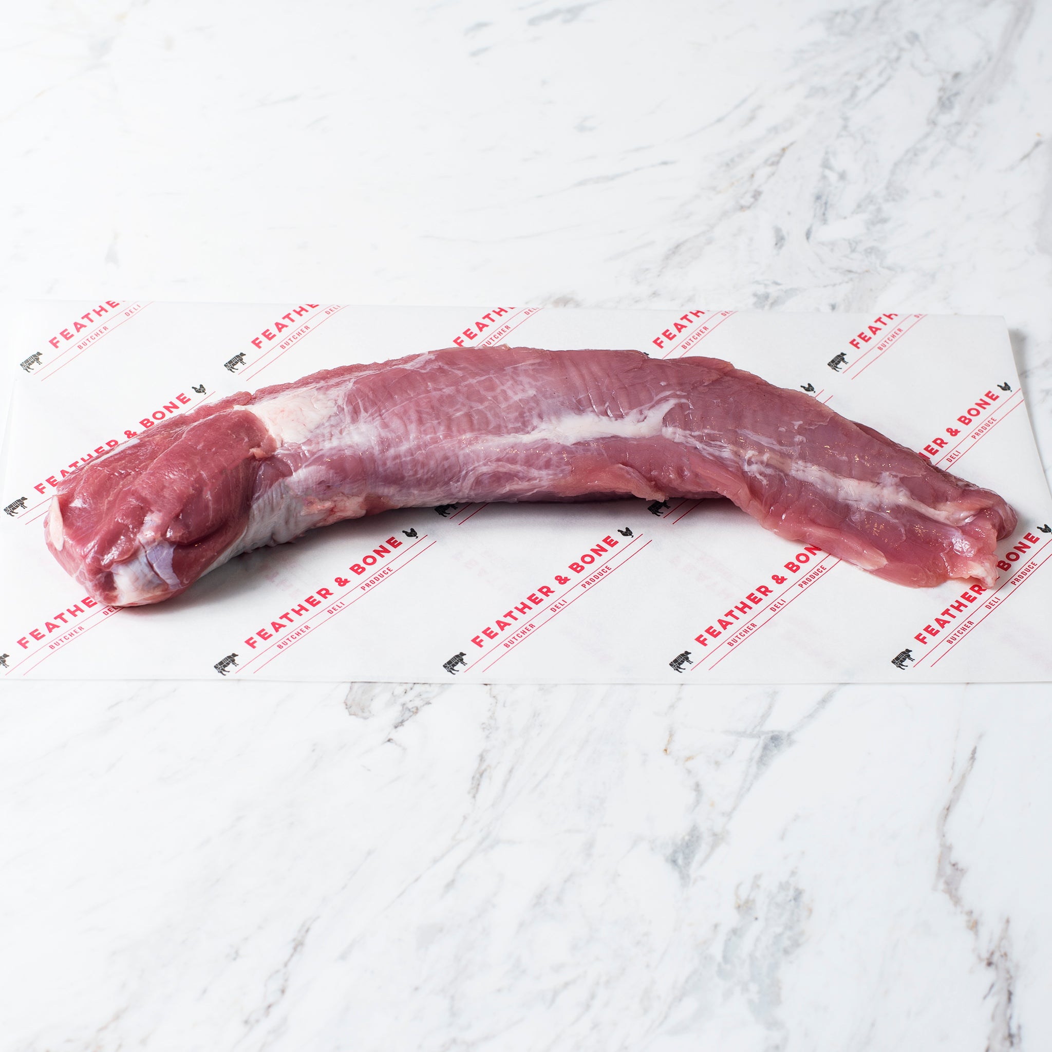 A 	 Free Range Pork Tenderloin 400g on feather & bone branded paper on a marble table top.