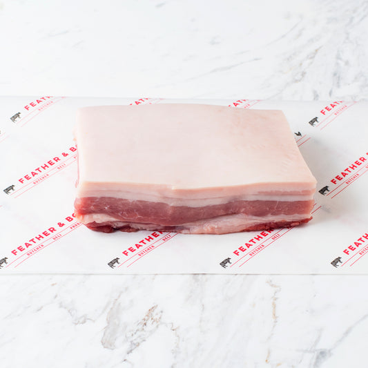 A piece of Free Range Pork Belly on a marble table.