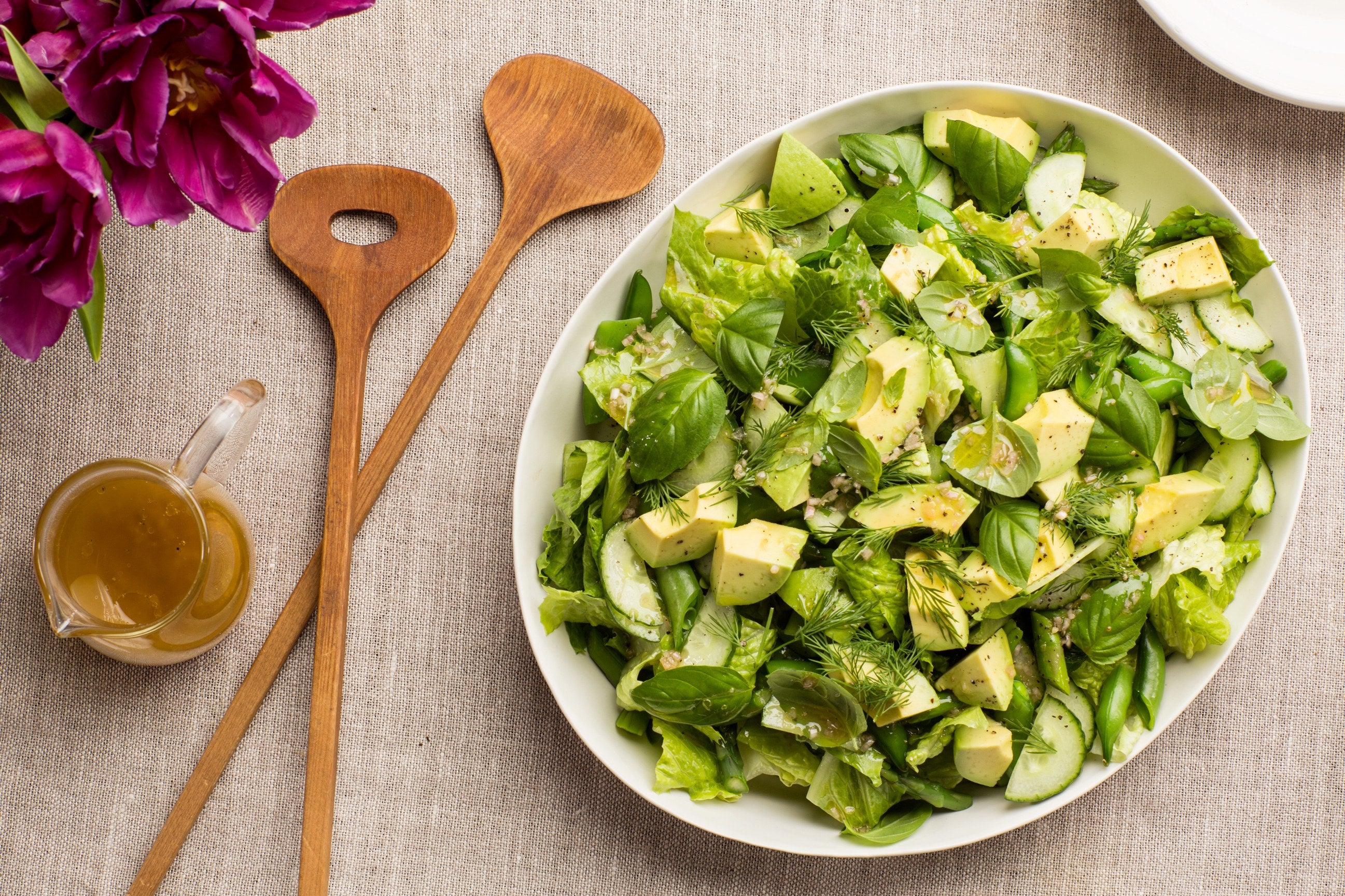 A green tossed salad with wooden salad servers.