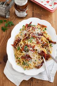 A white plate with spaghetti and sund dried tomatoes.
