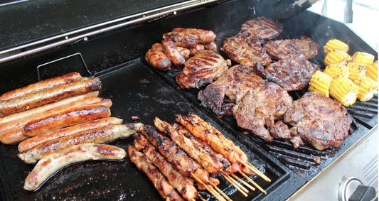 A selection of steaks, sausages and chicken skewers on a bbq.